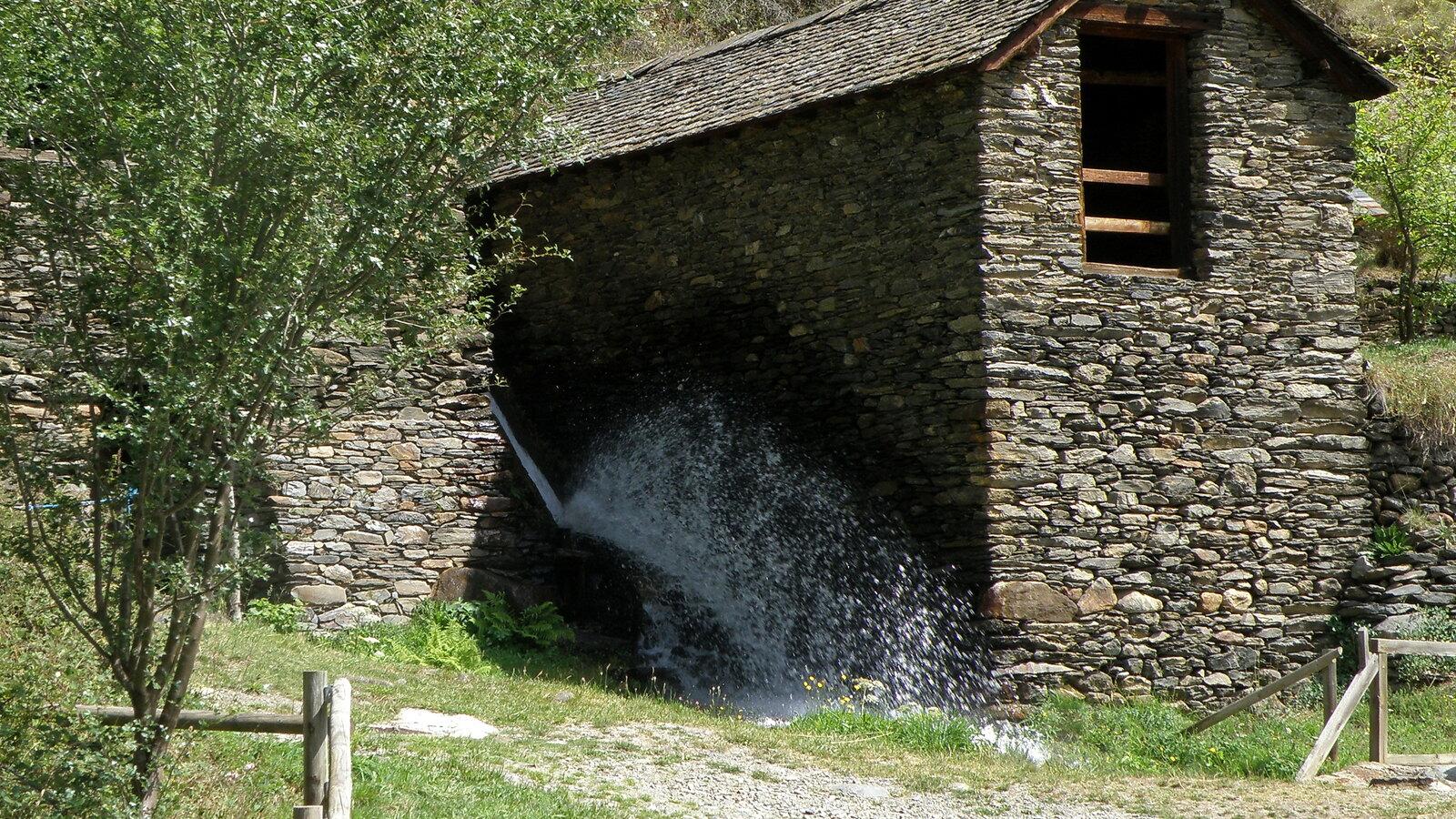 Water rushing between the slate walls of the historic sawmill and flour mill at Àreu