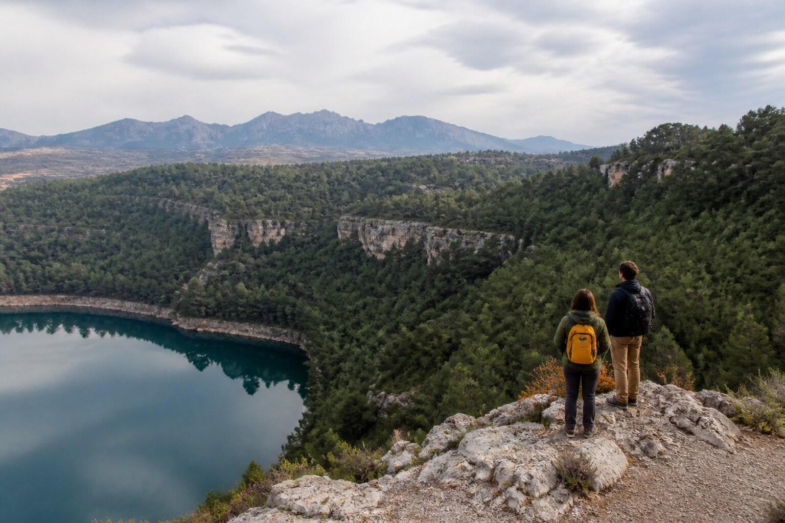Hikers overlooking a lake and wooded Moianès landscape